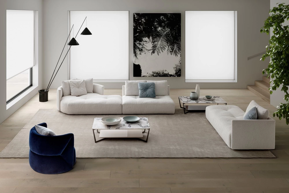 Tento obývací pokoj nechává světlo a volný prostor, aby udělaly dojem. Modulární pohovka a keramický konferenční stolek dodávají prostoru základní styl, zatímco solitérní designové křeslo v osobité modré barvě nese oživení minimalistického interiéru.