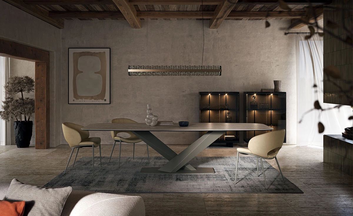 Stůl s robustní podnoží, obklopený hladkými liniemi židlí, dominuje místnosti, kde tradiční prvky a moderní design tvoří dokonalou symbiózu.